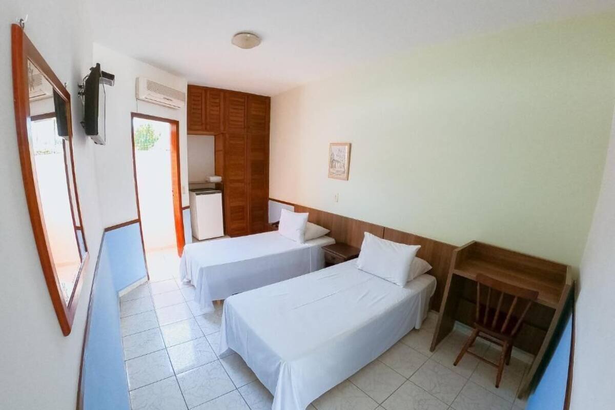 A hotel room with two single beds, a wooden headboard, a small table, and a mirror.