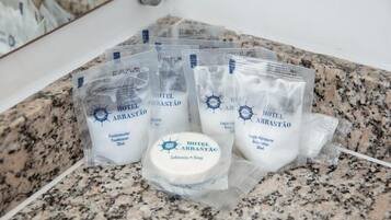 Varios artículos de tocador en bolsas de plástico con la etiqueta 'Hotel Arrastão' sobre una encimera de granito.
