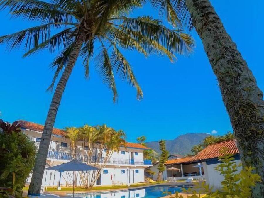 A resort with a swimming pool, palm trees, and a mountain in the background.