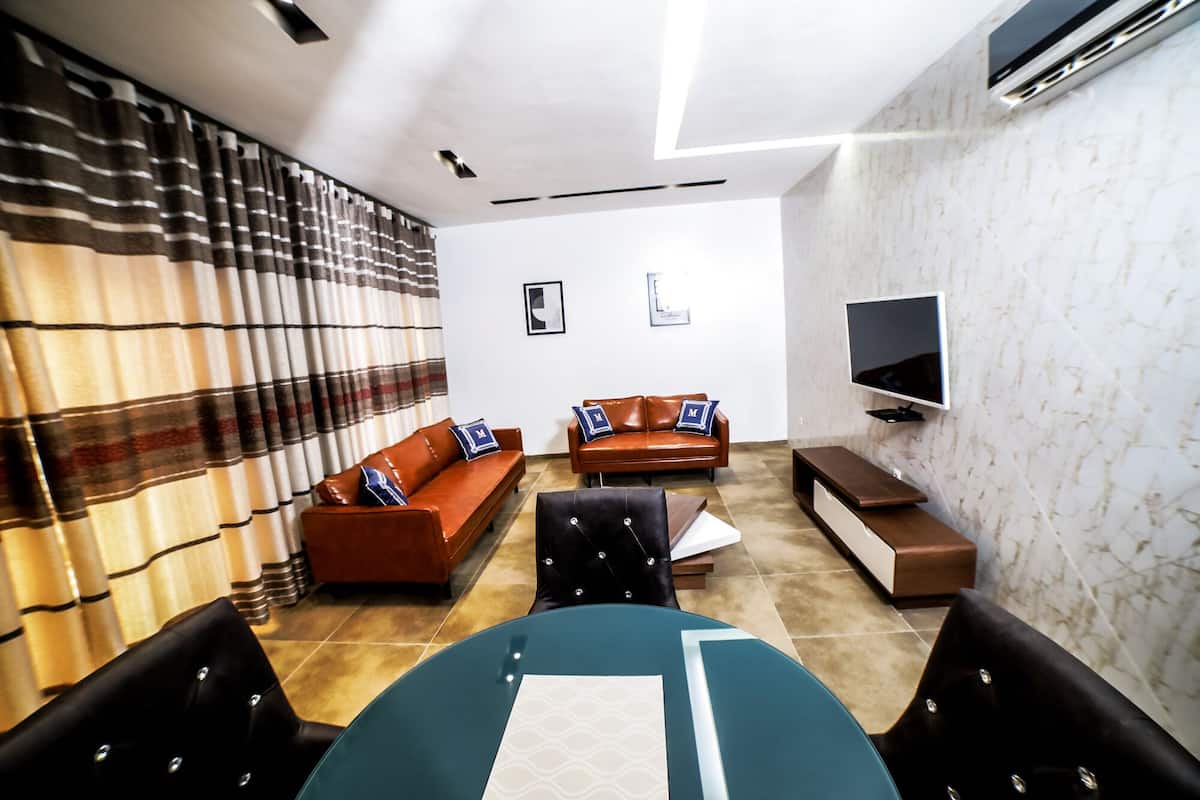 A modern living room with a sofa, armchairs, a coffee table, and a flat-screen TV.