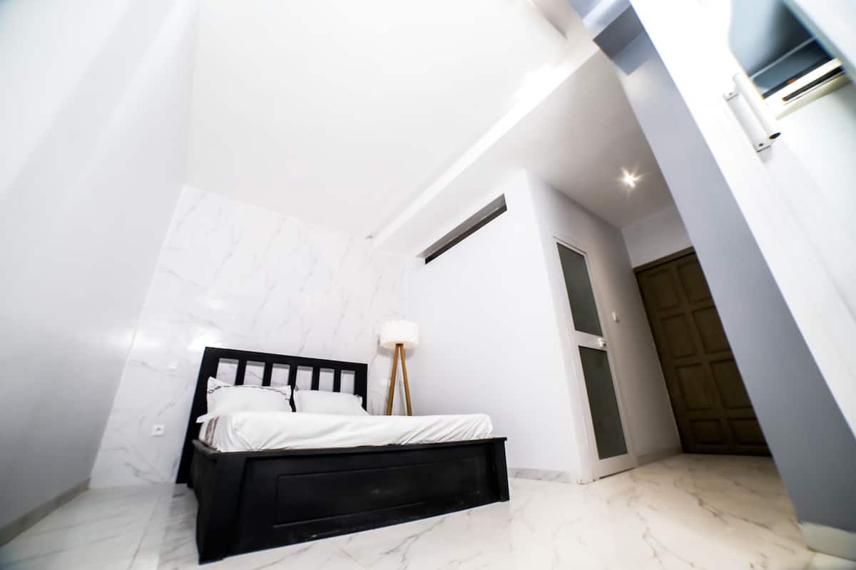 A bedroom with a bed, a nightstand, and a lamp.