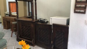 Un salon avec une table basse en bois, un canapé, un téléviseur fixé au mur et un tableau représentant des pommes vertes.