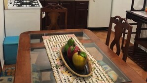 Une cuisine de taille réduite, avec des meubles de rangement en bois foncé, un réfrigérateur blanc et une table à manger dotée d’un plateau en verre.