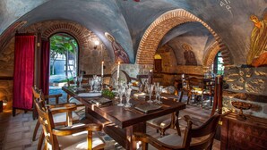 A dining area with a stone ceiling, arched brick walls, and a table set for four. - Acrotel Athena Villas (Sithonia)