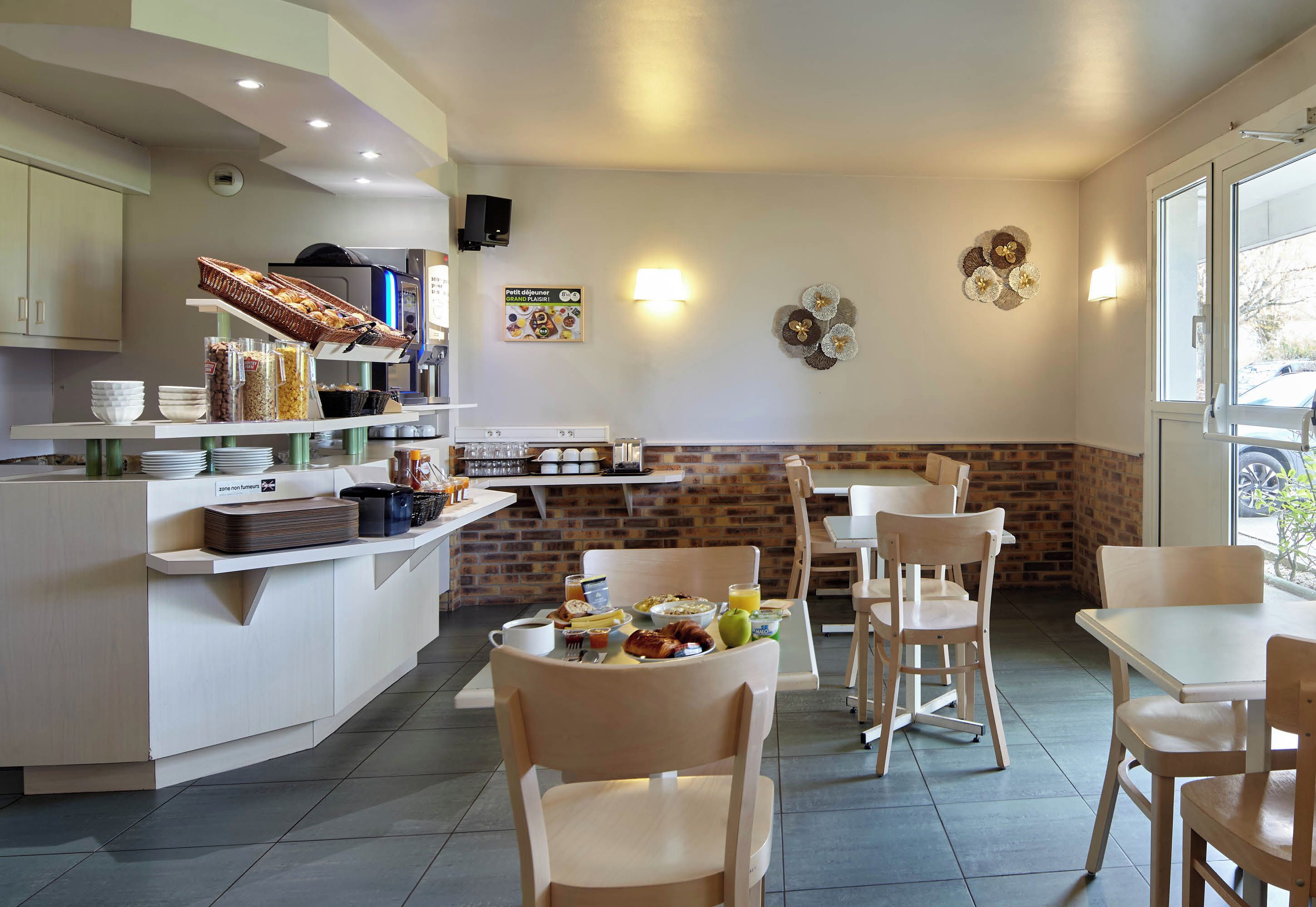 A modern breakfast area with a buffet setup, seating, and a brick accent wall.