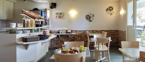 Un espace moderne dédié au petit-déjeuner, avec un buffet, des places assises et un mur décoratif en briques.