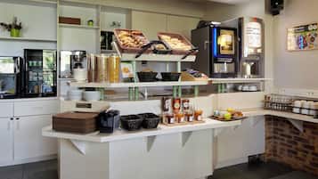 A breakfast bar with various food items, a coffee machine, and a clock on the wall.
