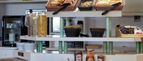 A bakery display with bread and pastries, jars of jam, and a coffee machine in the background.