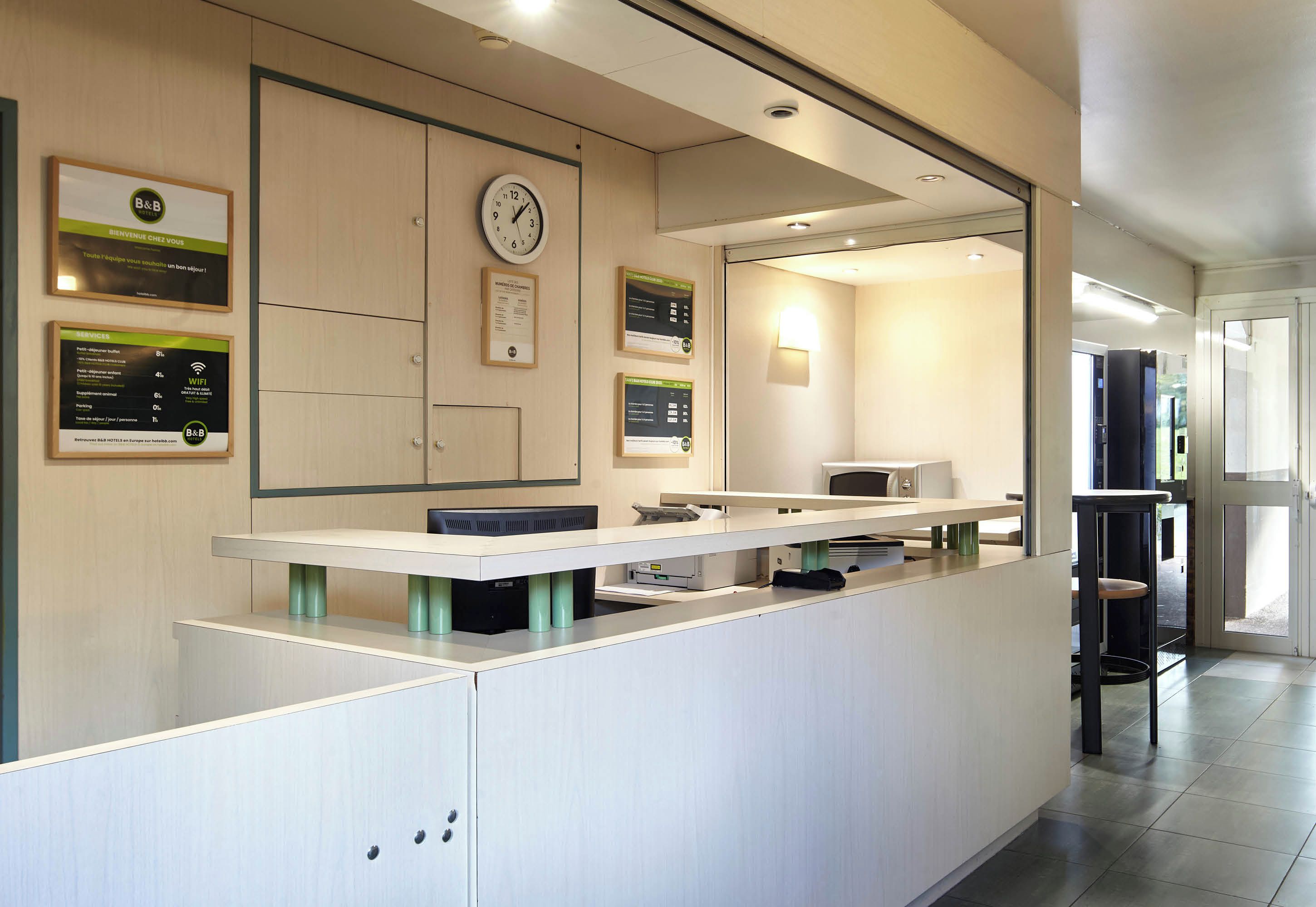A reception area with a reception desk, a clock, and informational posters on the wall.