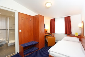 A hotel room with a bed, a desk, a chair, a wardrobe, and a shower area. - Hotel Stadt Hannover oHG (Goettingen)