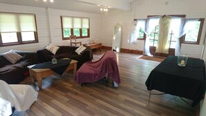 Un salón amplio con suelo de madera, un sofá marrón, una mesa de centro de madera y una mesa negra con una vela.