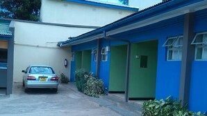 A building with a blue and white exterior, a car parked in front, and a small garden area. - Nanyuki Simba Lodge (Nanyuki)