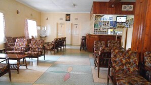 A lobby with multiple seating areas, a reception desk, and a television screen. - Nanyuki Simba Lodge (Nanyuki)