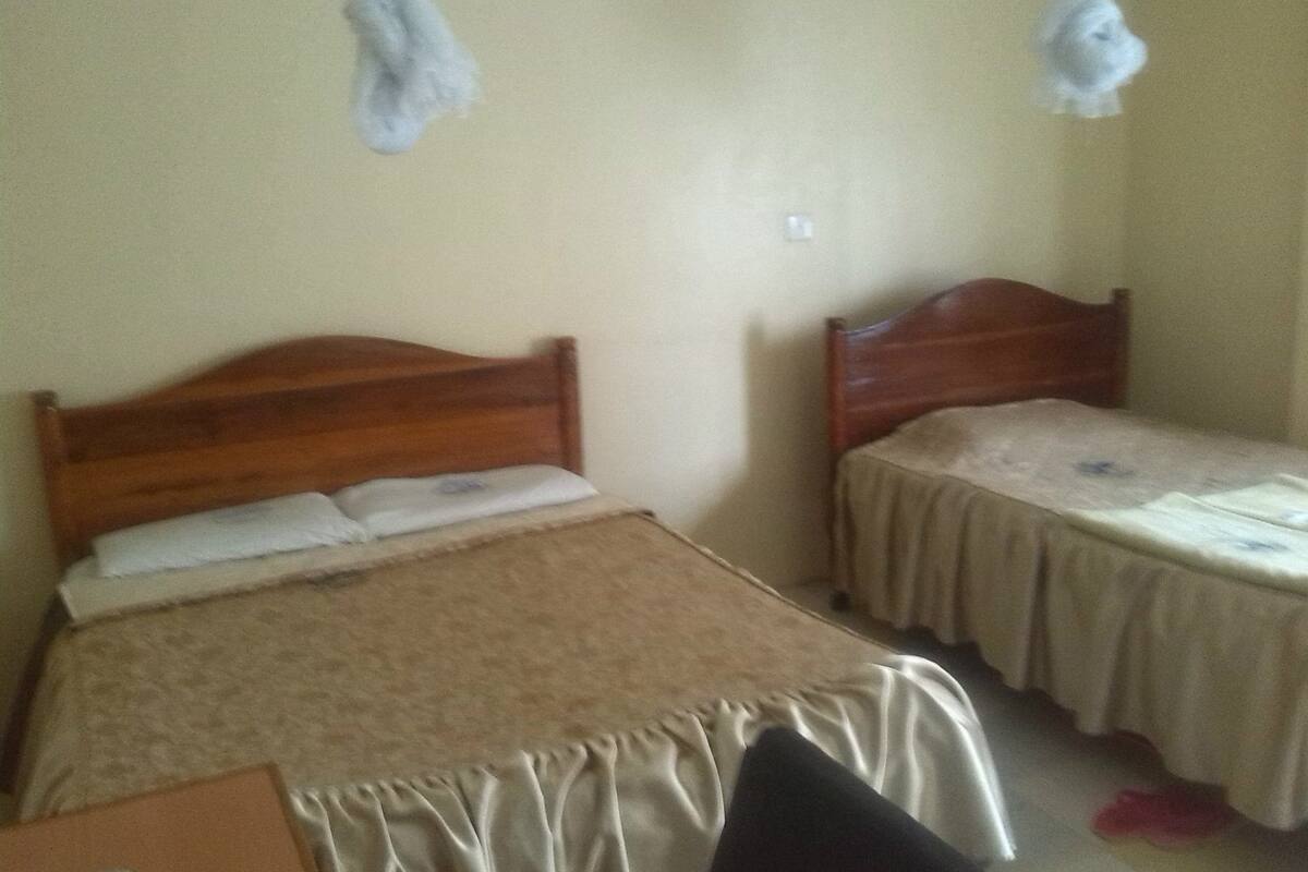 A room with two wooden beds, each with a headboard, a bedside table, and a chair.