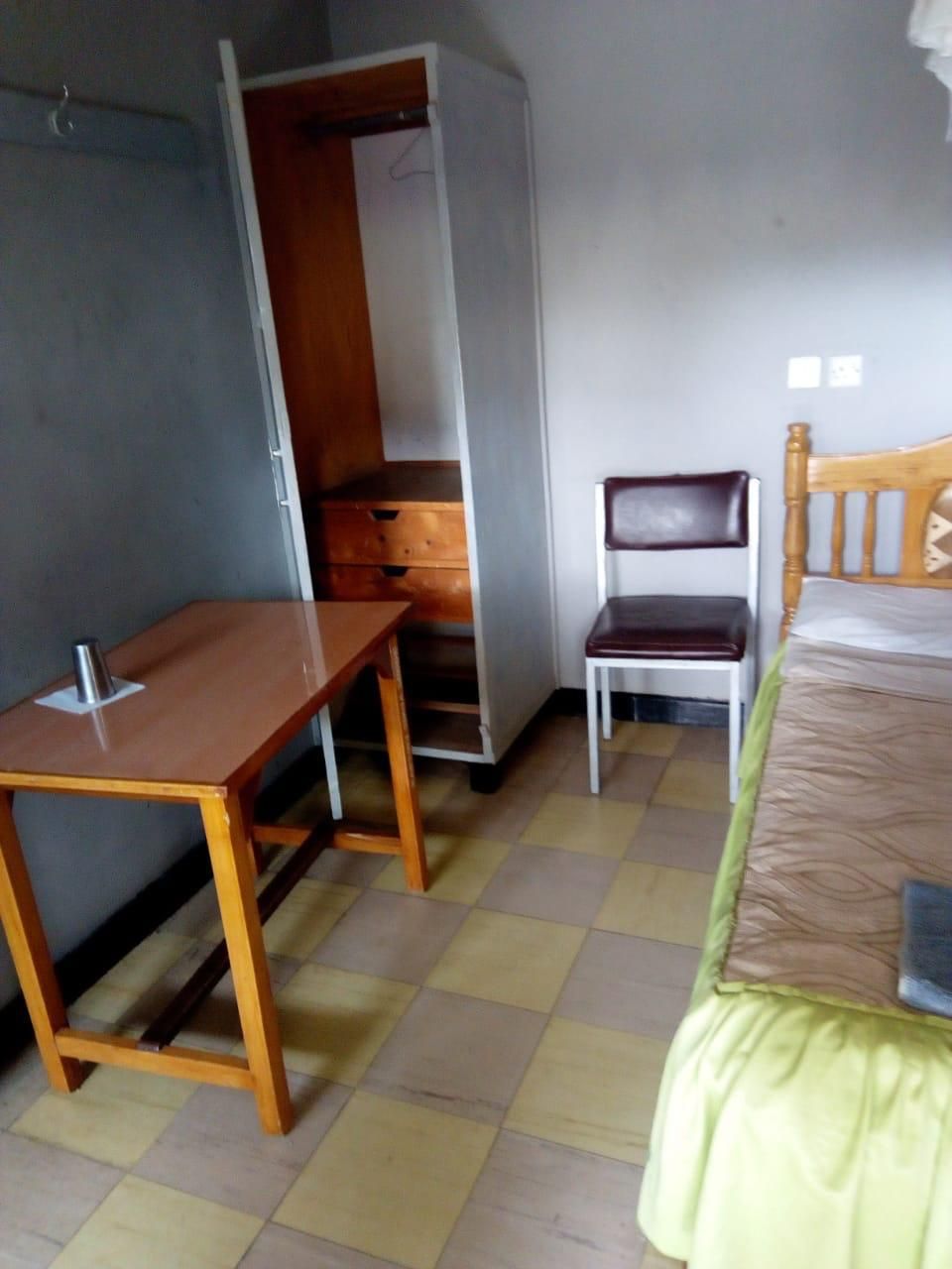 A room with a bed, a wooden chair, a desk, and a wardrobe.