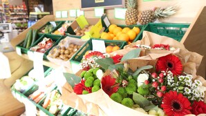 A grocery display with fresh produce and flower bouquets.