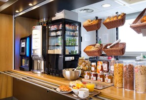 A breakfast buffet with various food items, a coffee machine, and baskets of bread. - B&B Hotel Cannes La Bocca Plage (Cannes)