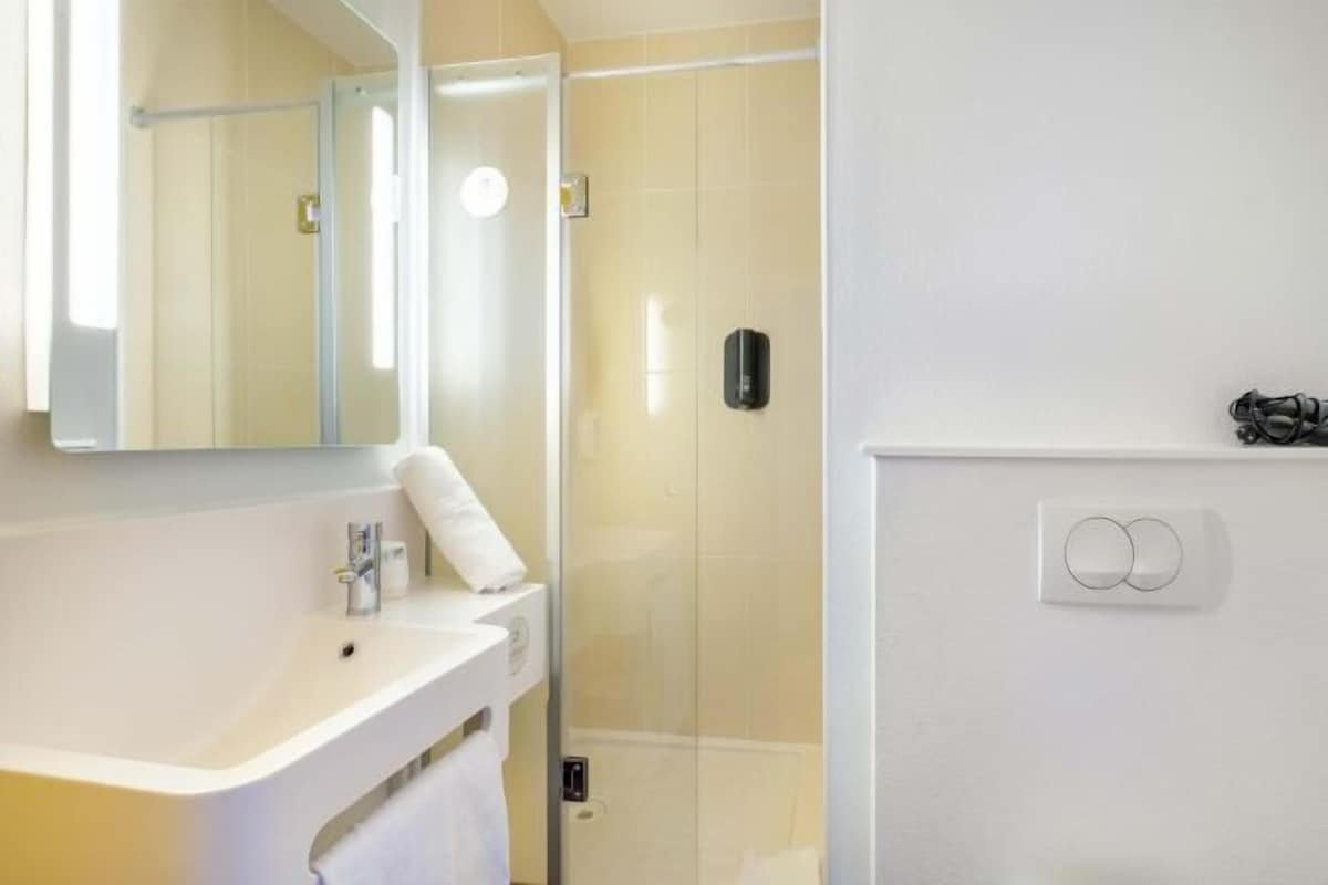 Une salle de bain avec un lavabo blanc, un miroir et une cabine de douche.