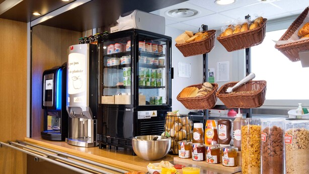 Ein Frühstücksbuffet mit verschiedenen Speisen, einer Kaffeemaschine und Brotkörben.
