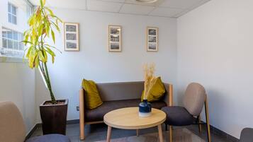 A modern waiting area with a sofa, chairs, a round table, and a potted plant.