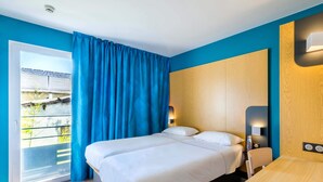 Ein Hotelzimmer mit Bett, Tisch und Blick nach draußen.