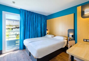 A hotel room with a bed, a table, and a view of the outside. - B&B Hotel Cannes La Bocca Plage (Cannes)
