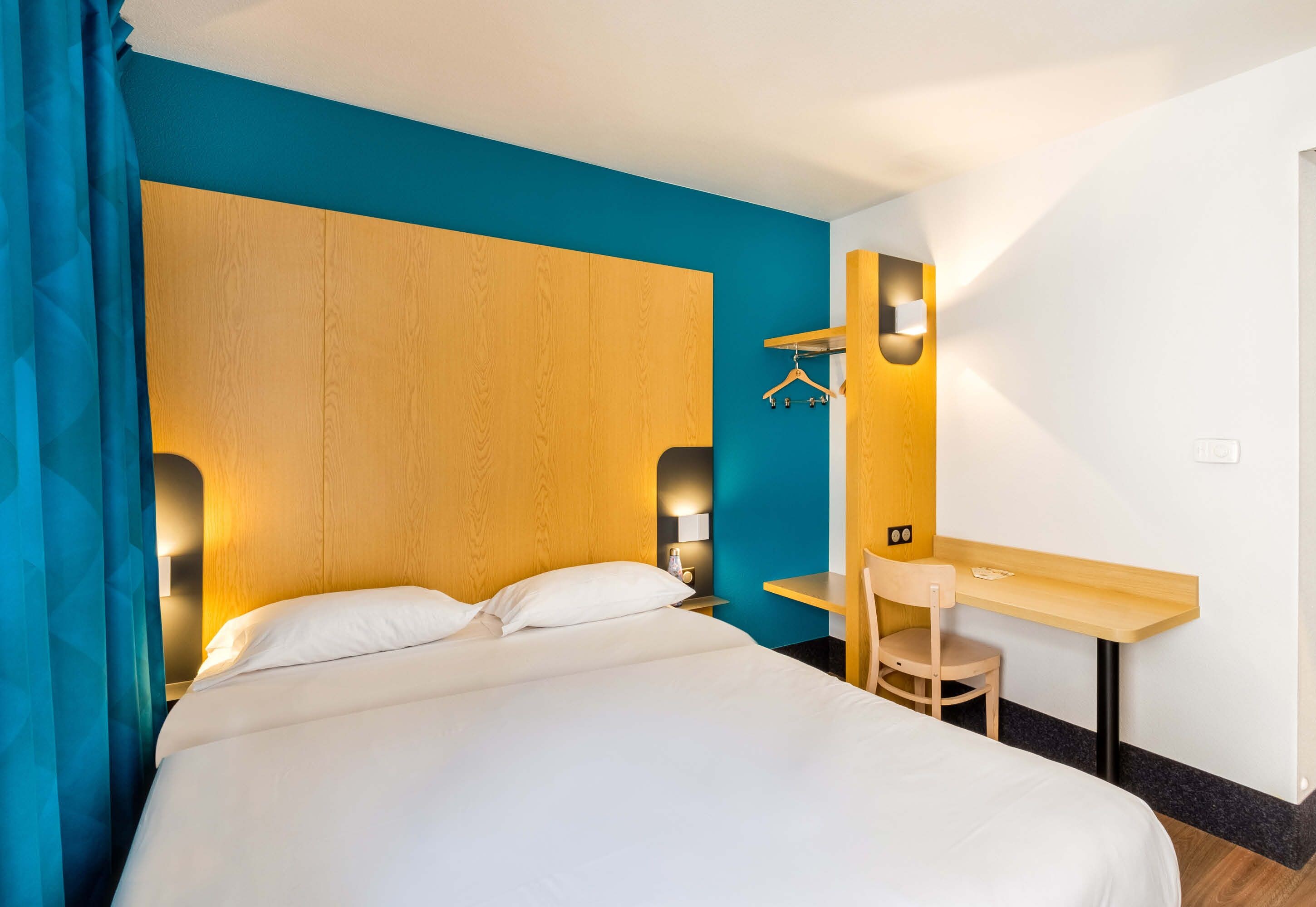 A hotel room with a bed, a desk, and a chair.