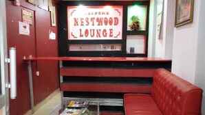 A red leather couch and a reception desk with a 'Welcome Nestwood Lounge' sign. - Nestwood Hotel (Nanyuki)
