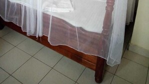 A bed with a wooden frame and a canopy. - Nestwood Hotel (Nanyuki)