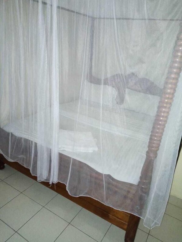 A bed with a mosquito net and wooden headboard.