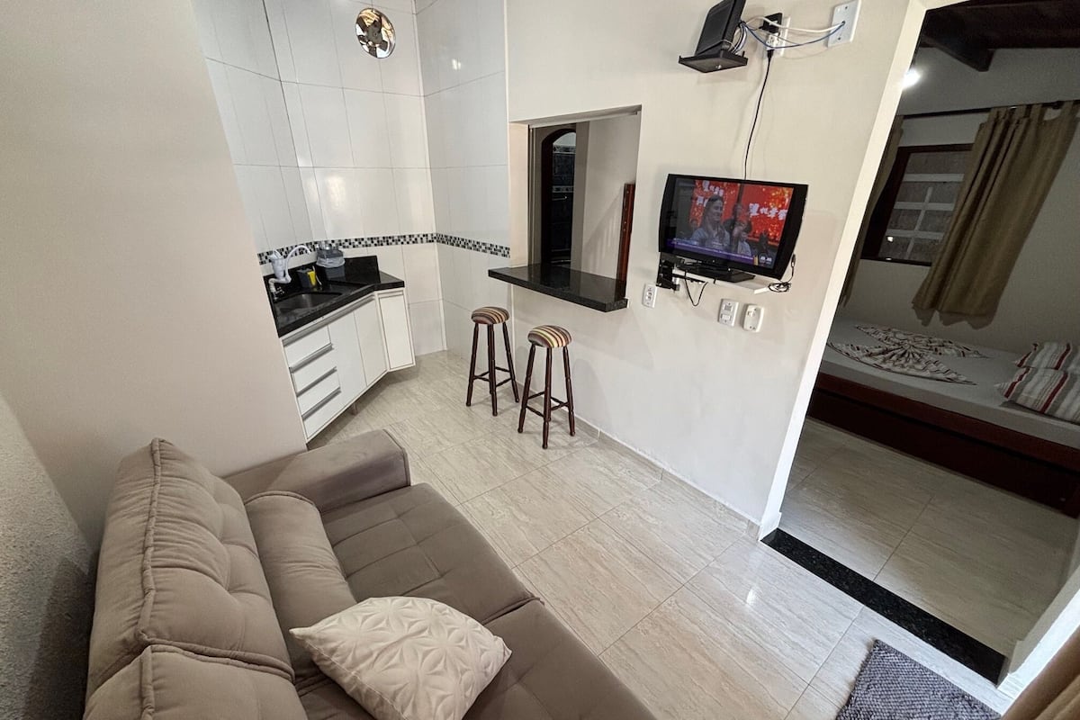 Una sala moderna con sofá, cocina, televisor y cama.