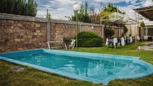 A swimming pool with a brick wall, a lamp post, and a covered area with tables and chairs. - Hotel Francesco (San Rafael)