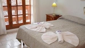 A hotel room with a bed, a nightstand with a lamp, and a window with a view. - Hotel Francesco (San Rafael)