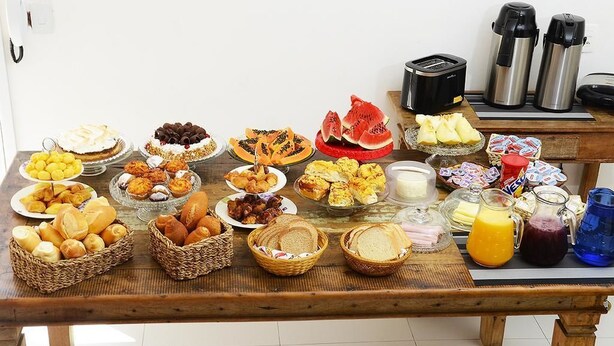 Um buffet de café da manhã com diversos pães, frutas e bebidas.