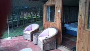 Una cabaña de madera con dos sillones de mimbre y una cama.