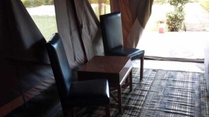 Una habitación con carpa, una mesa y dos sillas, un tapete estampado y vistas al exterior.