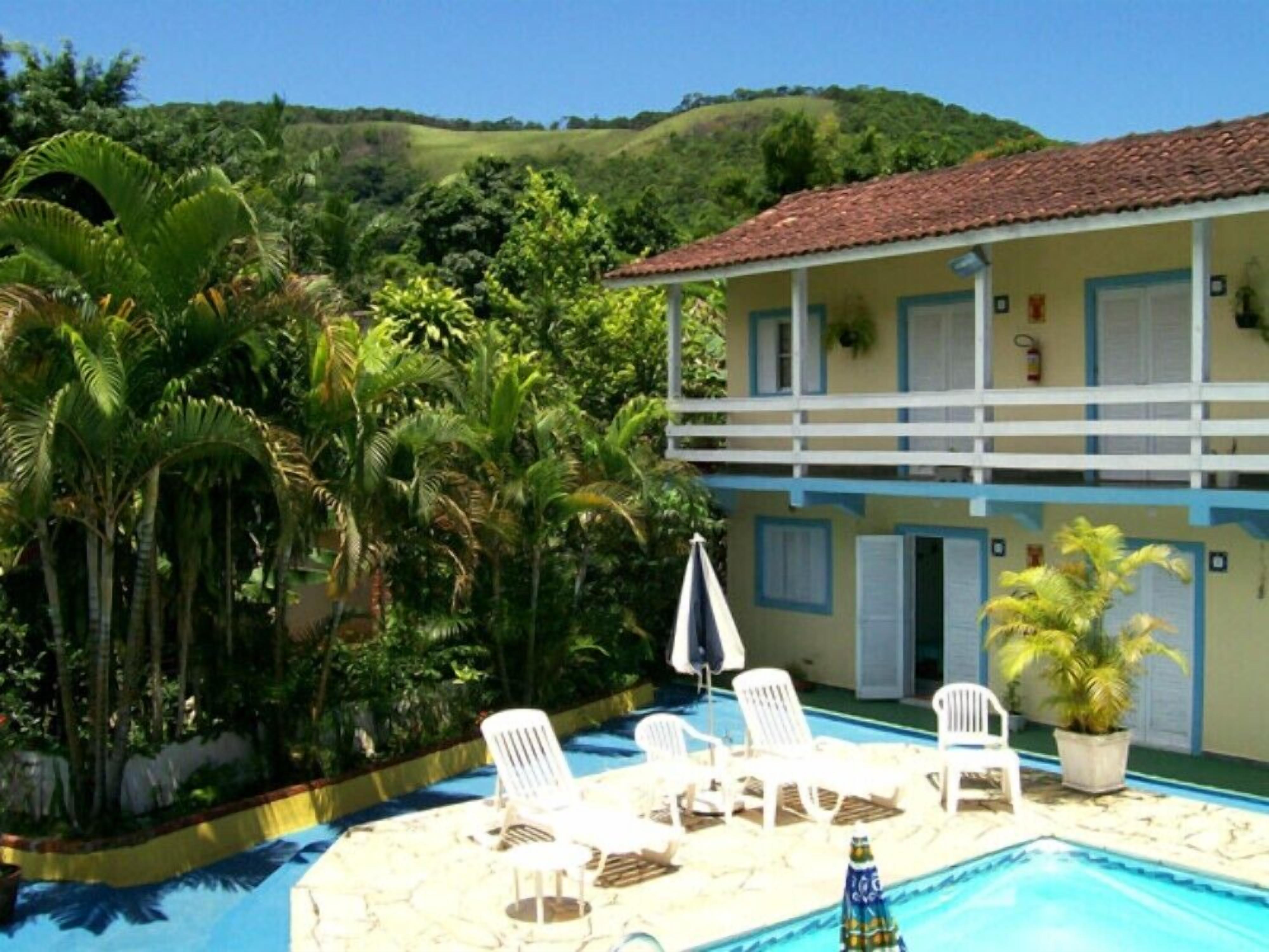 A pool area with lounge chairs and a building with a tiled roof.