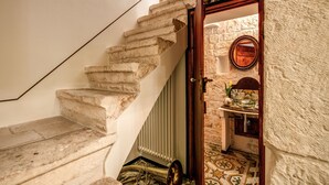 Una escalera de piedra que lleva a una habitación con suelo de baldosas, un radiador y una puerta de madera.