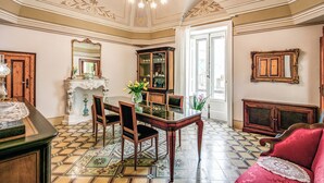 Un comedor con mesa de vidrio, sillas de madera, candelabro y piso estampado.