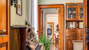 Un piano de madera, un jarrón verde con plantas y un aparador de madera con puertas de vidrio.