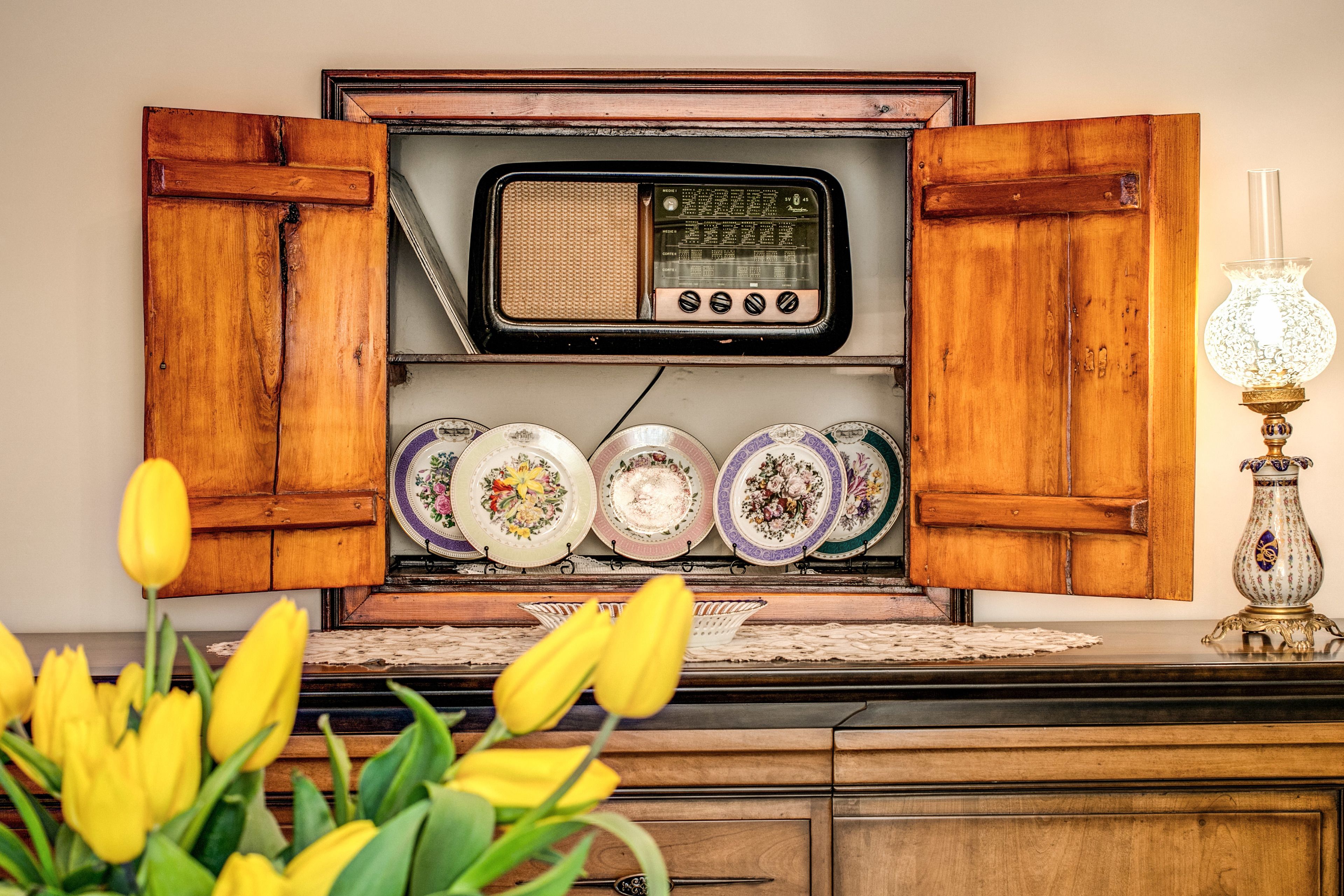 Un poste de radio ancien, installé sur un meuble en bois et agrémenté de plaques décoratives en dessous.
