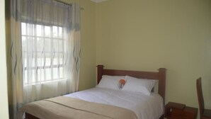 Una cama individual con cabecera de madera, una mesita de noche y una silla.