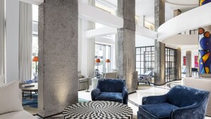 Un vestíbulo amplio con techos altos, ventanas grandes y mobiliario moderno.