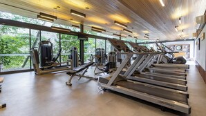 A gym with treadmills, weight machines, and a large window offering a view of greenery. - Spa Posse do Corpo (Petrópolis)