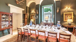 A formal dining room with a long table set for a meal, surrounded by wooden chairs with red cushions. - Wardhill Castle (Inverurie)