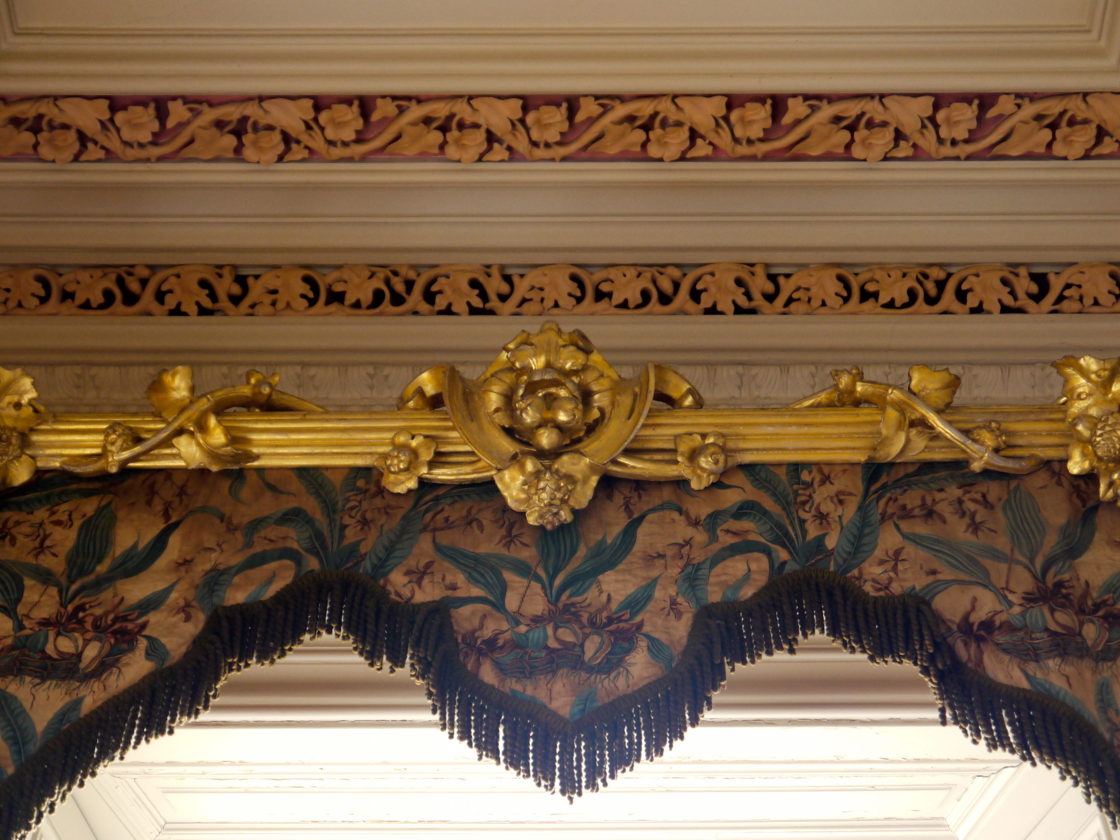 A detailed ceiling with ornate gold decorations and floral patterns.