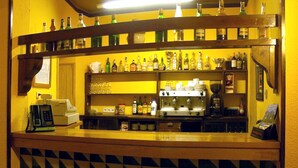 A bar area with shelves of bottles, a coffee machine, and a patterned tile floor. - Hostal Les Collades (Sort)
