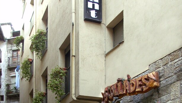 A narrow street with buildings featuring balconies and a sign for "Hotel de la Plage". - Hostal Les Collades (Sort)