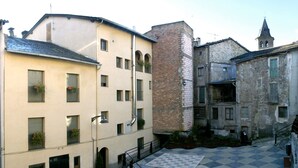 A courtyard with a checkered floor, surrounded by buildings with balconies and windows. - Hostal Les Collades (Sort)