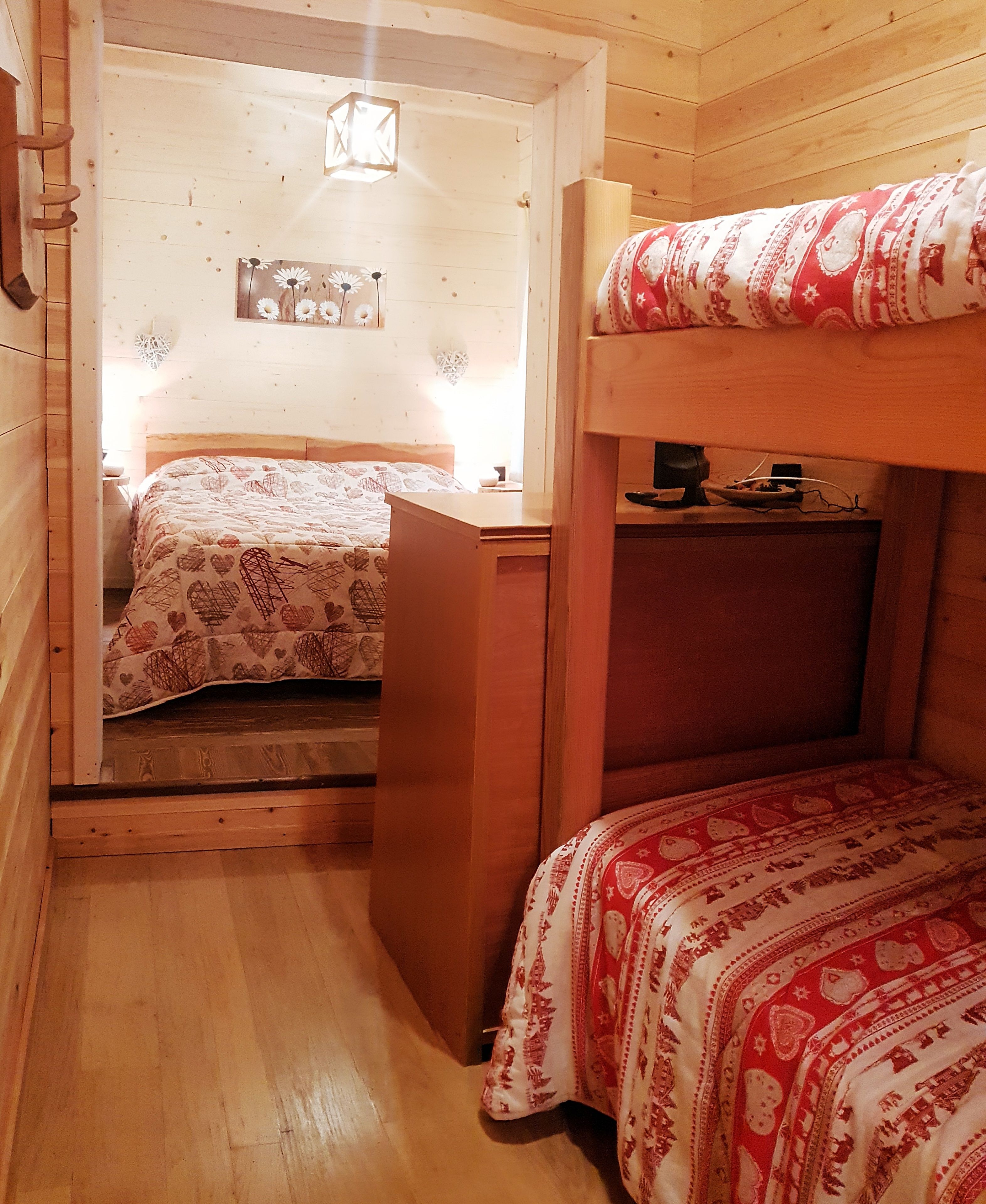 Una stanza accogliente con un letto a castello, una scrivania e un letto con copripiumino floreale.